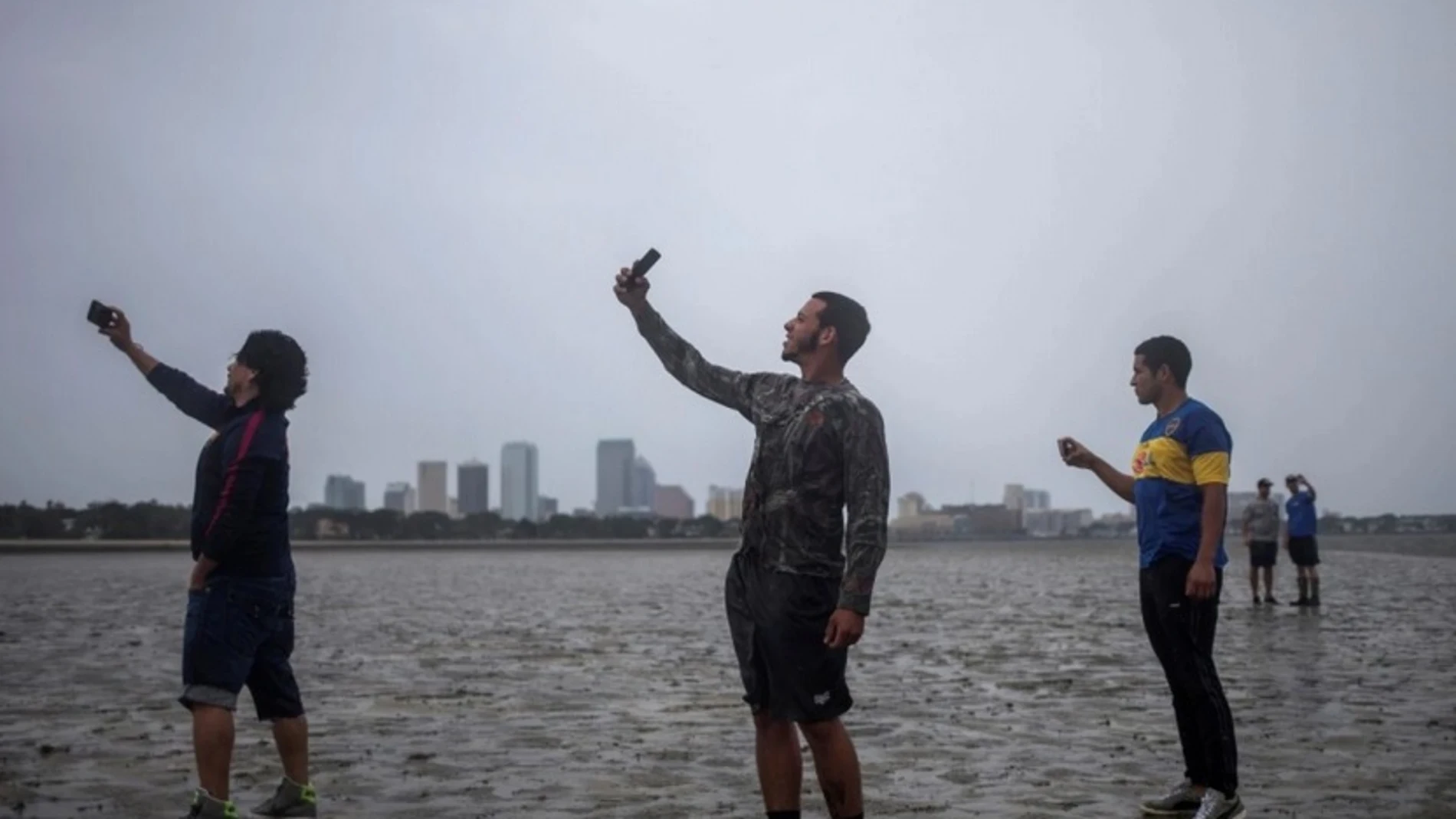 Varias personas se hacen selfies en la costa con el mar retirado Varias personas se hacen selfies en la costa con el mar retirado