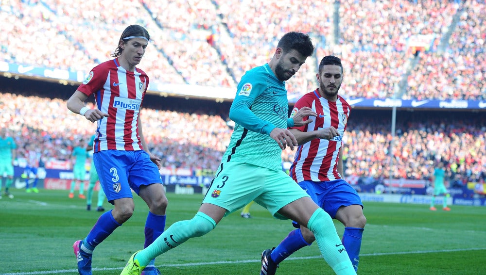 Piqué intenta despejar el balón ante la presión de Filipe Luis y Koke