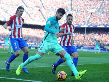 Piqué intenta despejar el balón ante la presión de Filipe Luis y Koke