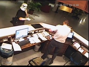 Un hombre, disfrazado con una máscara de la Guerra de las Galaxias, atraca a punta de pistola al recepcionista de un hotel