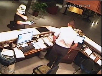 Un hombre, disfrazado con una máscara de la Guerra de las Galaxias, atraca a punta de pistola al recepcionista de un hotel
