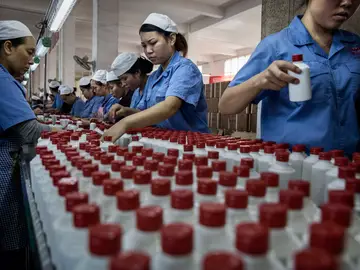 Trabajadores chinos organizando botellas de baijiu Trabajadores chinos organizando botellas de baijiu