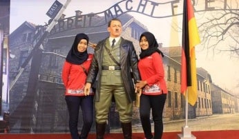 Dos mujeres haciéndose una foto con la estatua de Hitler
