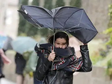 Una mujer combate los fuertes vientos y la lluvia Una mujer combate los fuertes vientos y la lluvia