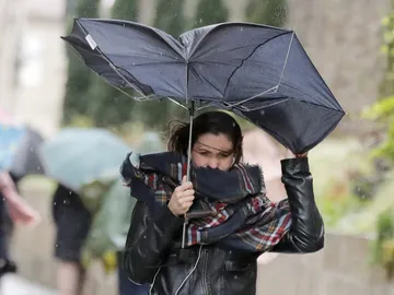 Una mujer combate los fuertes vientos y la lluvia Una mujer combate los fuertes vientos y la lluvia