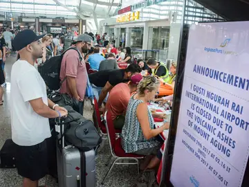 Turistas escuchan información sobre sus vuelos tras la erupción del volcán Agung en el aeropuerto Ngurah Rai en Denpasar en Bali (Indonesia) Turistas escuchan información sobre sus vuelos tras la erupción del volcán Agung en el aeropuerto Ngurah Rai en Denpasar en Bali (Indonesia)