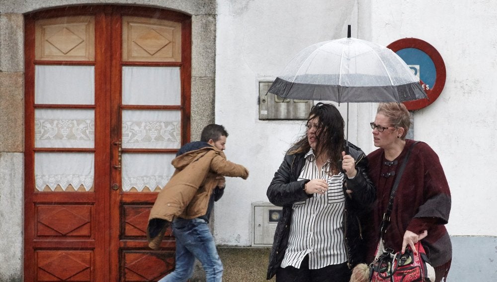 Vecinos de Melide se protegen de la lluvia y el viento
