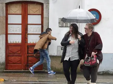 Vecinos de Melide se protegen de la lluvia y el viento Vecinos de Melide se protegen de la lluvia y el viento