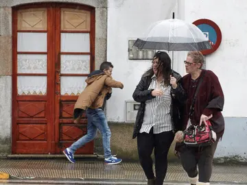 Vecinos de Melide se protegen de la lluvia y el viento Vecinos de Melide se protegen de la lluvia y el viento
