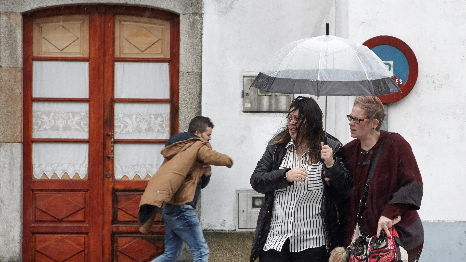 Vecinos de Melide se protegen de la lluvia y el viento Vecinos de Melide se protegen de la lluvia y el viento