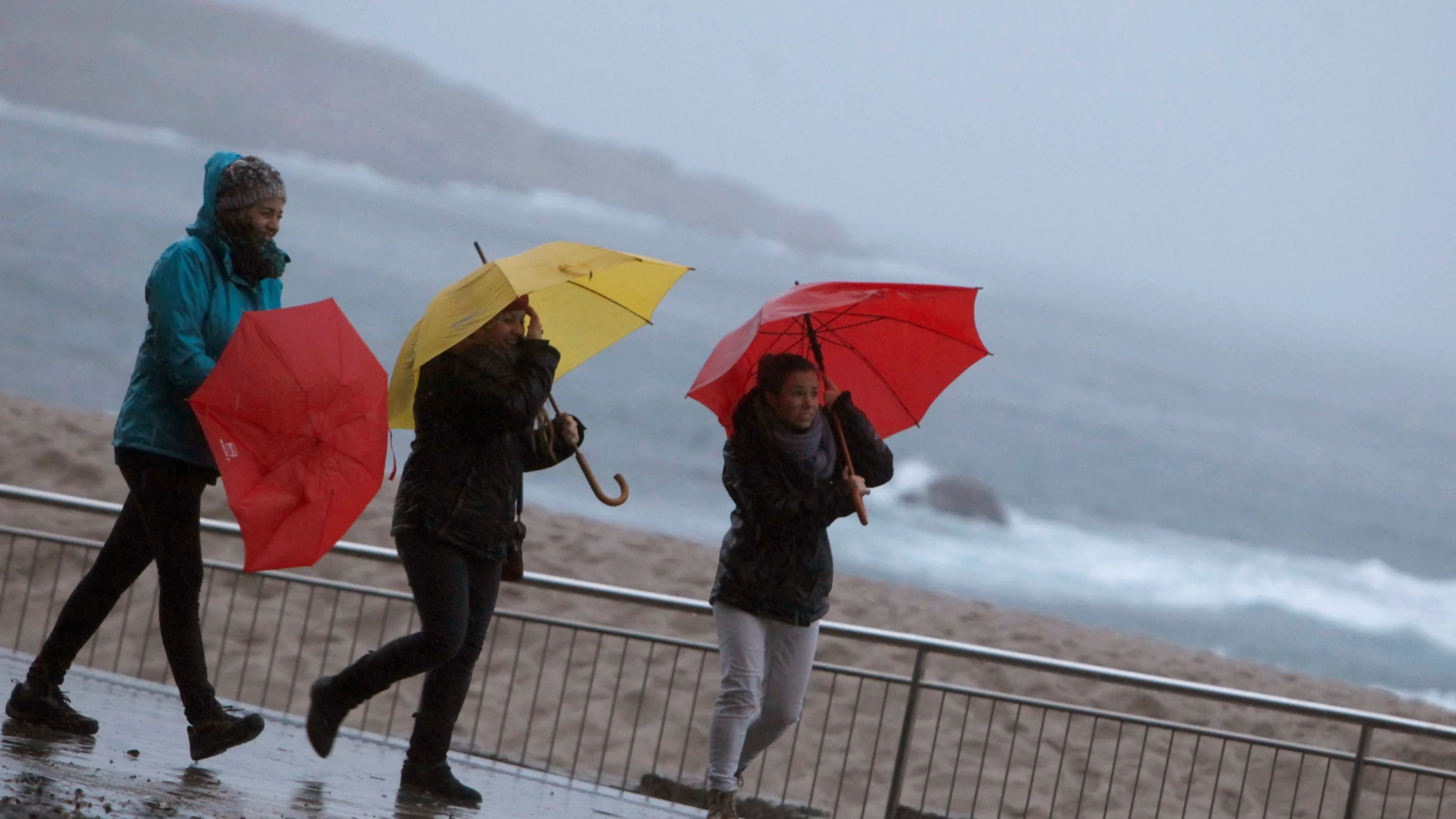 Tres mujeres se protegen de la lluvia en el paseo marítimo de A Coruña Tres mujeres se protegen de la lluvia en el paseo marítimo de A Coruña