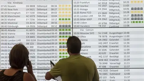 Dos viajeros observan el panel de salidas del aeropuerto de Bruselas Dos viajeros observan el panel de salidas del aeropuerto de Bruselas