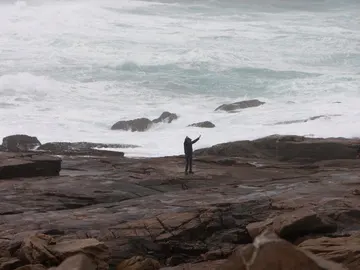 Dos personas se fotografían junto al oleaje en la zona de Cabo Silleiro Dos personas se fotografían junto al oleaje en la zona de Cabo Silleiro
