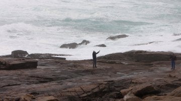 Dos personas se fotografían junto al oleaje en la zona de Cabo Silleiro