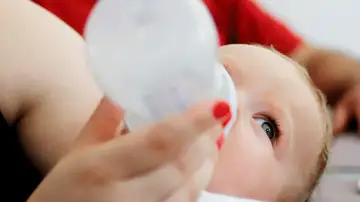 Un bebé tomando un biberón de leche Un bebé tomando un biberón de leche