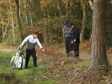 Un golfista consulta la posición de una bola a un árbitro durante un campeonato