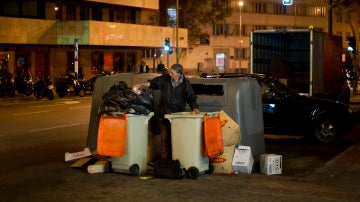 Un hombre buscando entre la basura