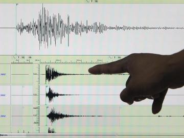 Un sismólogo señala un sismógrafo