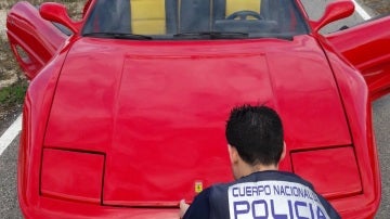 Un agente de la Policía Nacional junto al vehículo modificado para ser vendido como un Ferrari