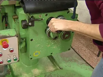Un trabajador manipula una máquina en una fábrica Un trabajador manipula una máquina en una fábrica