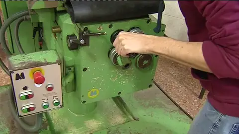 Un trabajador manipula una máquina en una fábrica Un trabajador manipula una máquina en una fábrica