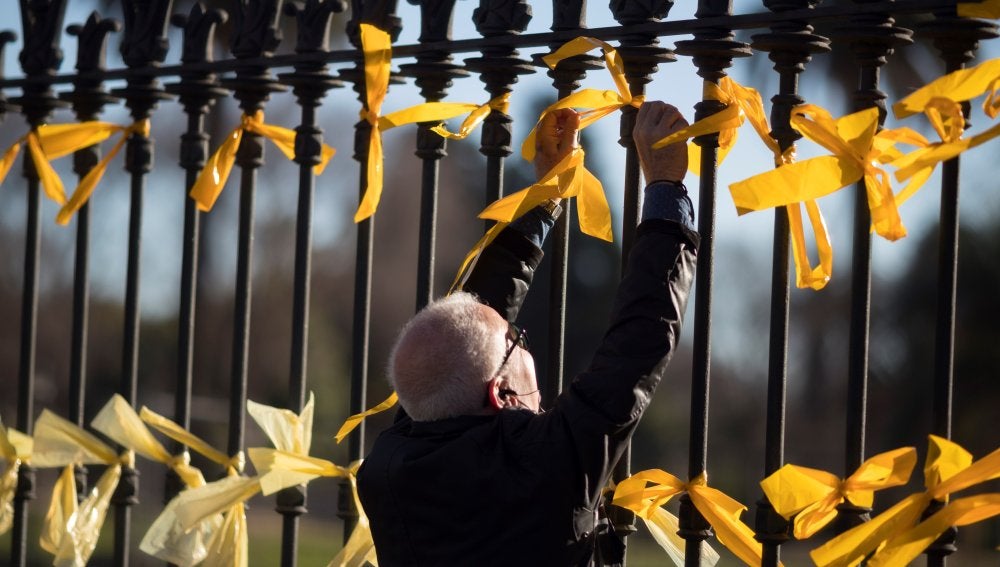 Un hombre coloca lazos amarillos en la verja del Pac de la Ciutadella (Archivo)