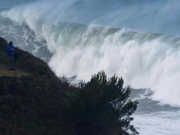 Un hombre fotografía las grandes olas que rompen ayer en la costa de la capital cántabra