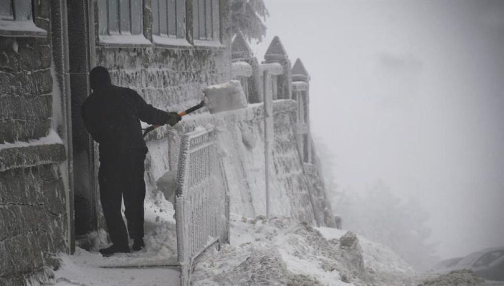 Un hombre retira la nieve de la puerta de una vivienda