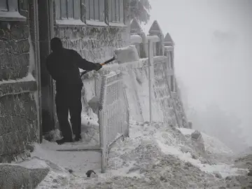 Un hombre retira la nieve de la puerta de una vivienda Un hombre retira la nieve de la puerta de una vivienda