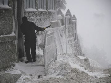 Un hombre retira la nieve de la puerta de una vivienda esta mañana en el Puerto de Navacerrada