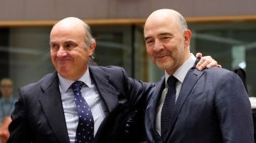 El ministro español de Economía, Luis de Guindos, saluda al comisario europeo de Economía y Asuntos Financieros, Pierre Moscovici