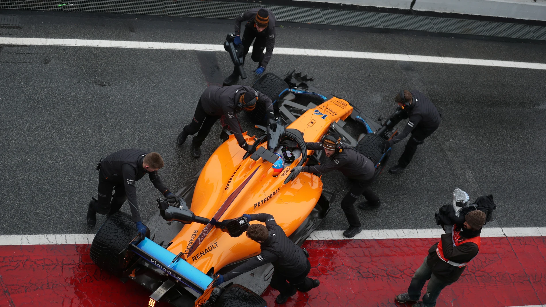Los mecánicos de McLaren meten el monoplaza de Alonso a boxes