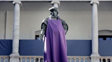Una estatua con un delantal morado en apoyo a la huelga del 8M
