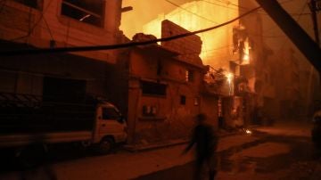 Personas caminan entre edificios en llamas después de presuntos ataques aéreos con fósforo blanco este viernes 