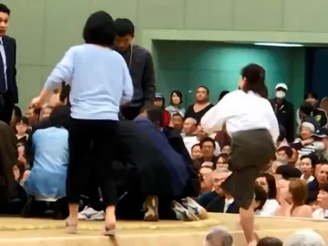 Varias mujeres tratan de reanimar a un hombre desfallecido en un ring de sumo Varias mujeres tratan de reanimar a un hombre desfallecido en un ring de sumo