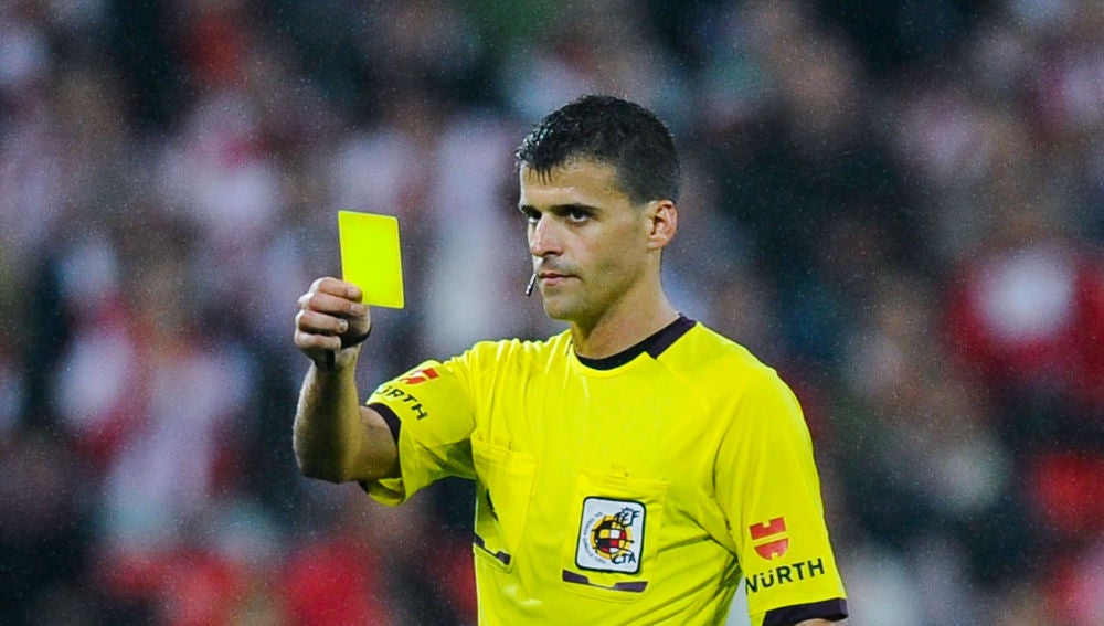 Gil Manzano muestra una tarjeta amarilla durante un partido