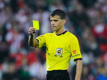 Gil Manzano muestra una tarjeta amarilla durante un partido
