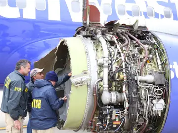 Investigadores examinando el daño a un motor del vuelo Investigadores examinando el daño a un motor del vuelo