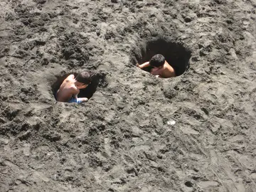 Niños cavando un agujero en la arena Niños cavando un agujero en la arena