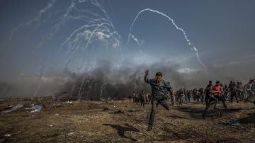 Manifestantes palestinos corren para refugiarse del gas lacrimógeno