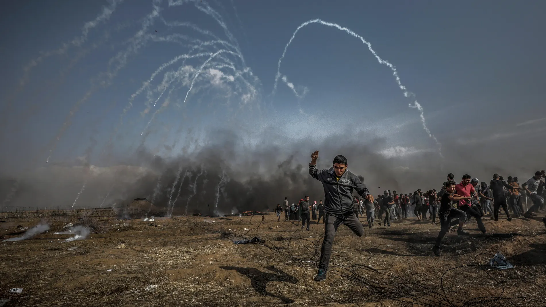 Manifestantes palestinos corren para refugiarse del gas lacrimógeno Manifestantes palestinos corren para refugiarse del gas lacrimógeno