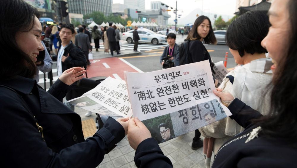 Varias personas leen la edición extra de un periódico local que informa de la histórica reunión de los líderes de las dos Coreas