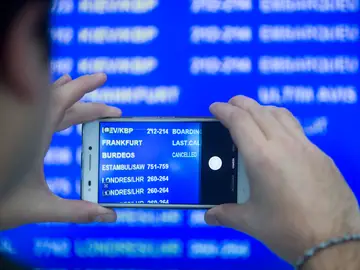 Un viajero fotografía el panel de salidas en el aeropuerto de El Prat Un viajero fotografía el panel de salidas en el aeropuerto de El Prat