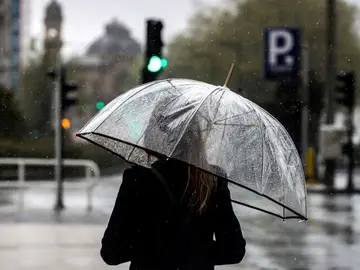 Una mujer camina bajo su paraguas Una mujer camina bajo su paraguas