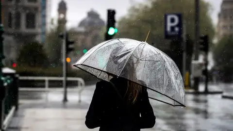 Una mujer camina bajo su paraguas Una mujer camina bajo su paraguas