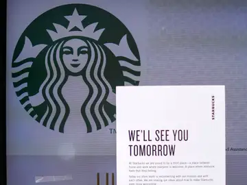 Vista de un local de Starbucks que tiene un letrero en el que se lee "Te veremos mañana" Vista de un local de Starbucks que tiene un letrero en el que se lee "Te veremos mañana"