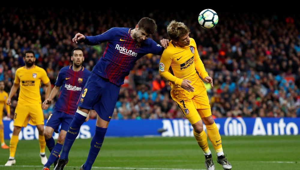 Piqué y Griezmann se disputan el balón por alto