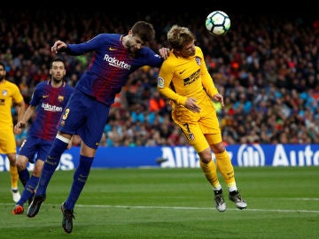 Piqué y Griezmann se disputan el balón por alto