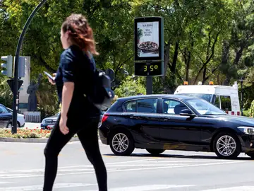 Una joven pasa junto a un termómetro que marca 35 grados centígrados Una joven pasa junto a un termómetro que marca 35 grados centígrados