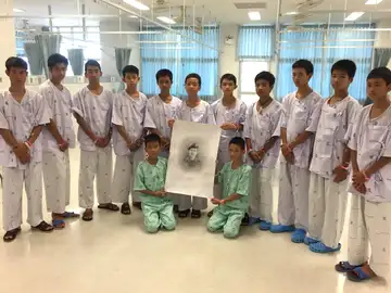 Los niños rescatados de la cueva posan junto a un retrato del buzo fallecido Los niños rescatados de la cueva posan junto a un retrato del buzo fallecido